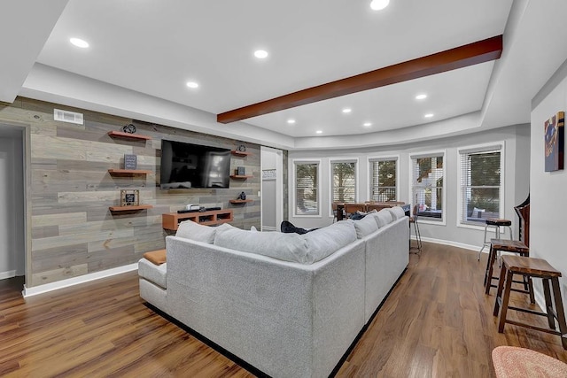 living room with beam ceiling, hardwood / wood-style flooring, wooden walls, and a tray ceiling