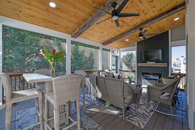 sunroom featuring wood ceiling, ceiling fan, a large fireplace, and lofted ceiling with beams