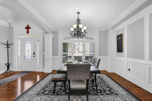 dining area featuring ornate columns, crown molding, dark hardwood / wood-style floors, and a chandelier