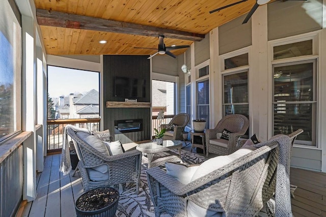 sunroom / solarium with lofted ceiling with beams, wooden ceiling, a large fireplace, and ceiling fan