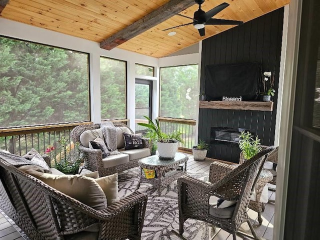 sunroom featuring wood ceiling, a large fireplace, ceiling fan, and vaulted ceiling with beams