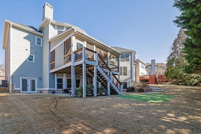 back of house featuring french doors, a sunroom, and a lawn