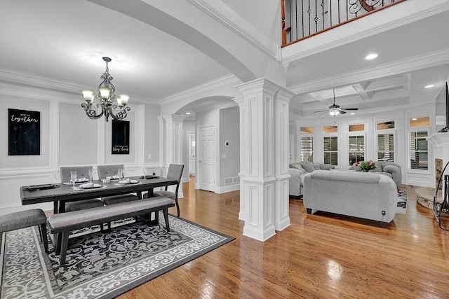 dining area with ornate columns, ceiling fan with notable chandelier, ornamental molding, coffered ceiling, and light hardwood / wood-style floors