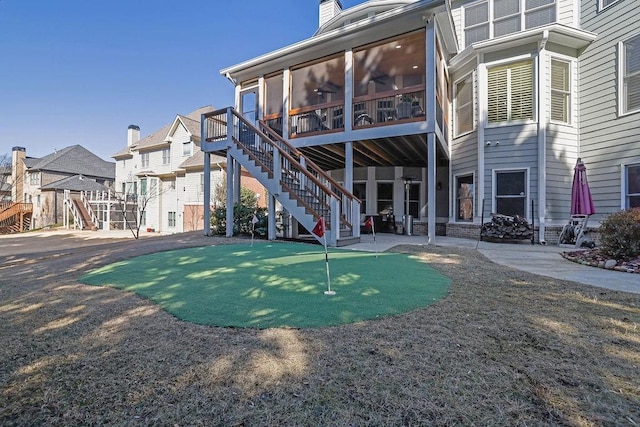 rear view of property with ceiling fan and a sunroom