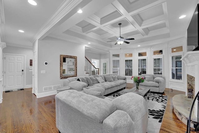 living room featuring crown molding, hardwood / wood-style flooring, a premium fireplace, coffered ceiling, and beamed ceiling