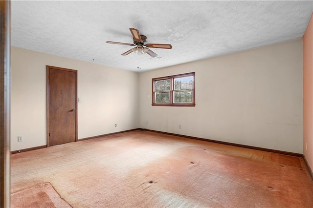 carpeted empty room featuring a ceiling fan, a textured ceiling, and baseboards