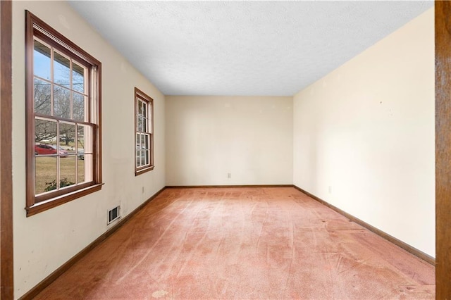 empty room featuring baseboards, visible vents, and light colored carpet