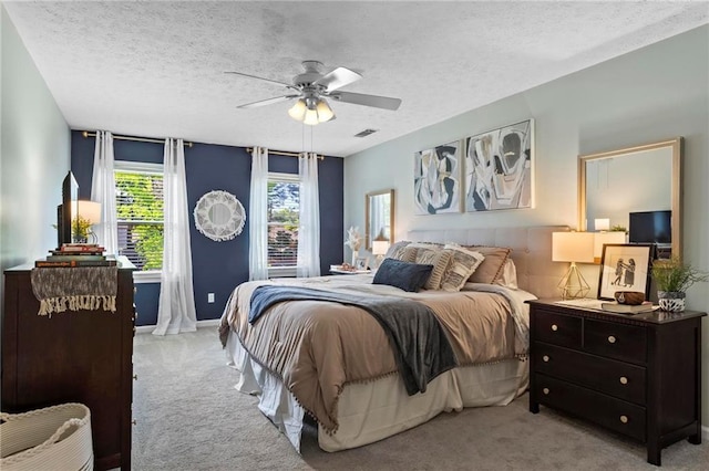 bedroom with a ceiling fan, a textured ceiling, light carpet, baseboards, and visible vents