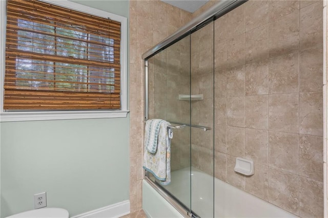 full bathroom featuring combined bath / shower with glass door, toilet, and baseboards