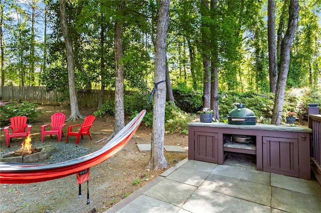view of patio / terrace featuring fence, a fire pit, and exterior kitchen