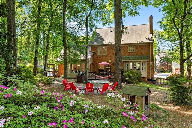 back of property with a fire pit, brick siding, and a chimney
