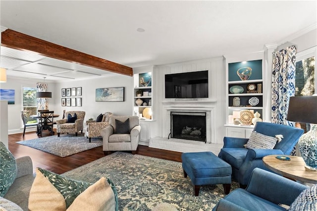 living area featuring wood finished floors, beam ceiling, baseboards, a brick fireplace, and built in shelves