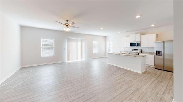 kitchen with ceiling fan, stainless steel appliances, light hardwood / wood-style floors, a wealth of natural light, and a kitchen island with sink