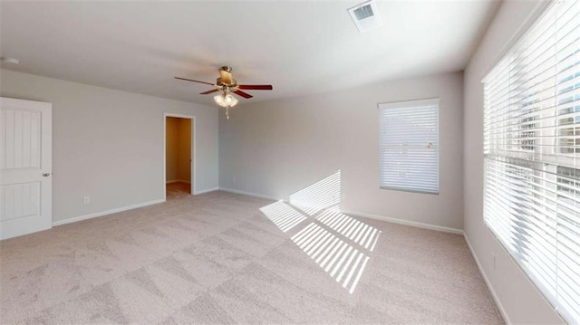 spare room with ceiling fan, light carpet, and plenty of natural light