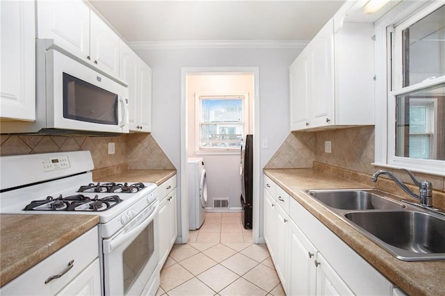 kitchen with sink, white cabinets, ornamental molding, washing machine and clothes dryer, and white appliances