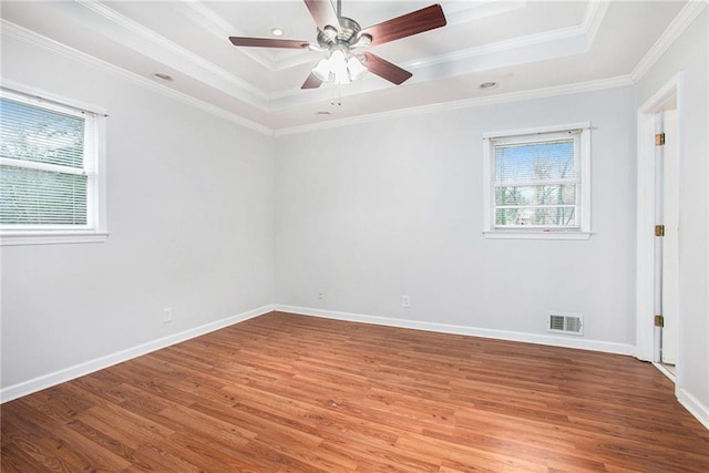 spare room featuring crown molding, ceiling fan, a tray ceiling, and light hardwood / wood-style flooring