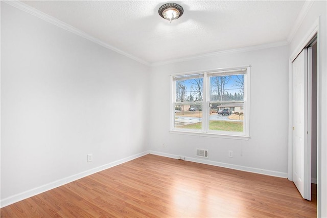 unfurnished bedroom with crown molding, light wood-type flooring, and a closet