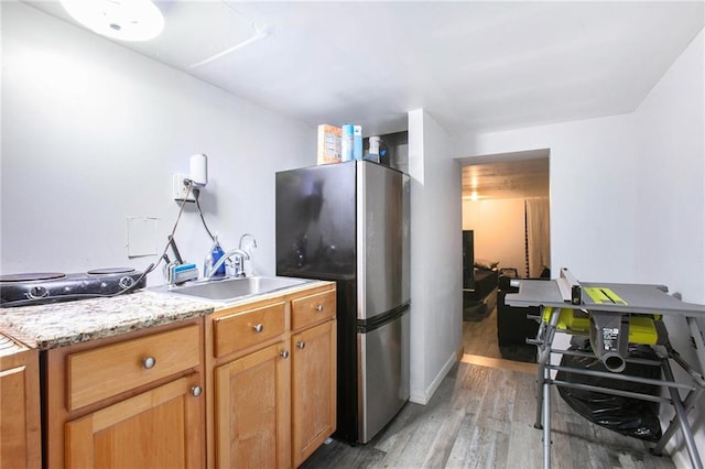 kitchen with stainless steel fridge, sink, and light wood-type flooring
