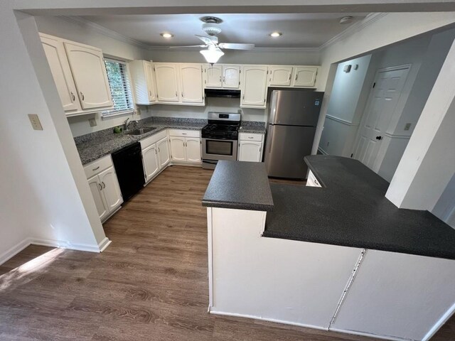 981 Dundee Dr, Lilburn, GA 30047 - kitchen featuring under cabinet range hood, stainless steel appliances, dark countertops, ornamental molding, and a sink