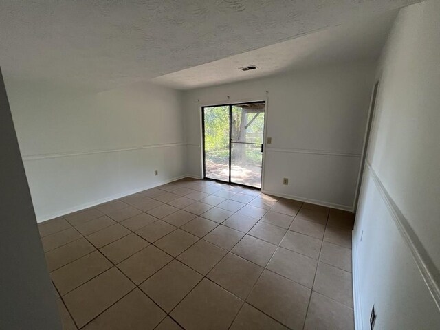 981 Dundee Dr, Lilburn, GA 30047 - tiled spare room featuring baseboards, a textured ceiling, and visible vents