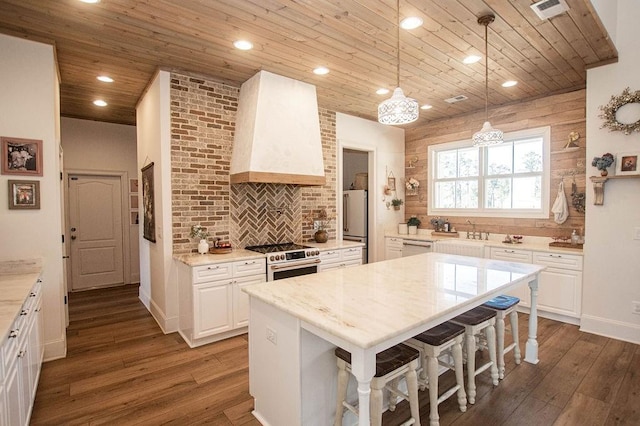 kitchen with wooden ceiling, wall chimney exhaust hood, visible vents, and premium appliances