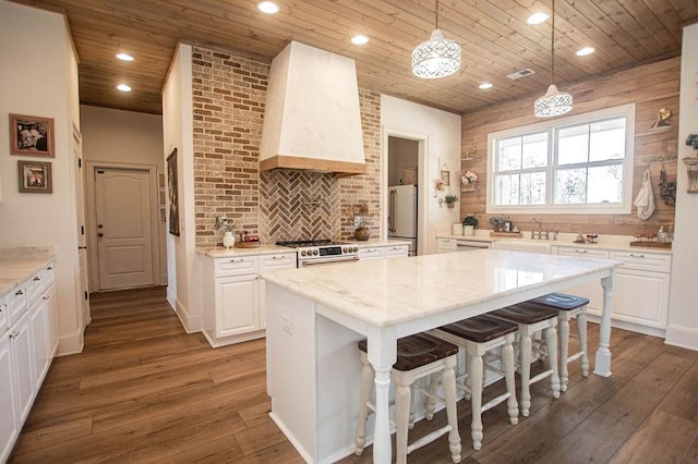 kitchen featuring wood-type flooring, high quality appliances, wall chimney exhaust hood, and wooden ceiling