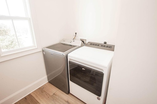 laundry area with light wood-style floors, a healthy amount of sunlight, washing machine and dryer, and laundry area