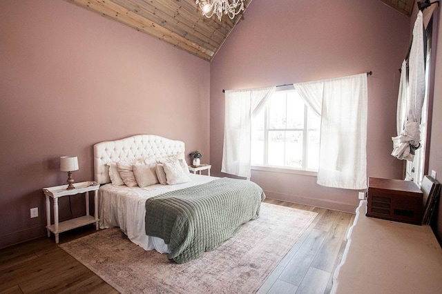 bedroom featuring an inviting chandelier, baseboards, lofted ceiling, and wood finished floors