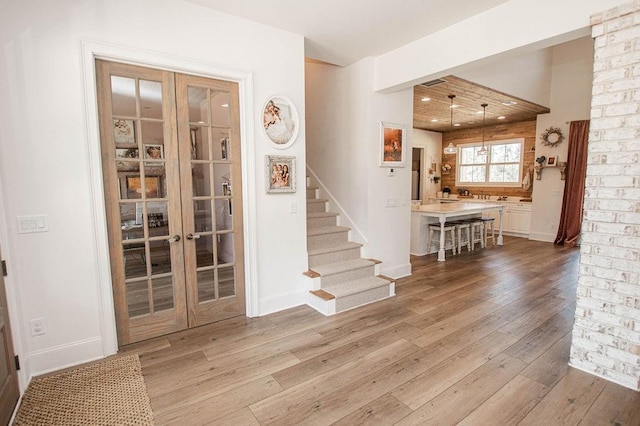 interior space with french doors, baseboards, light wood-style floors, and stairs