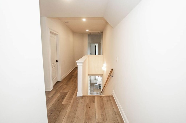 hallway with an upstairs landing, recessed lighting, light wood-style floors, baseboards, and attic access