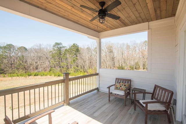 deck featuring a ceiling fan and a forest view