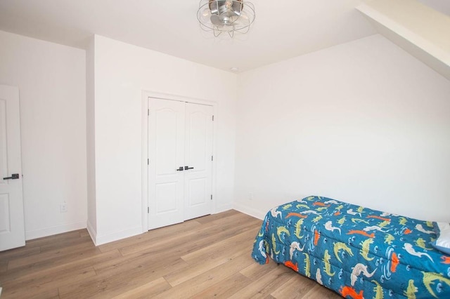 bedroom featuring wood finished floors, baseboards, and a closet