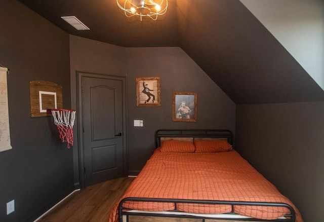 bedroom featuring visible vents, wood finished floors, an inviting chandelier, baseboards, and vaulted ceiling