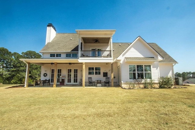 back of house with a lawn, french doors, a ceiling fan, and a balcony