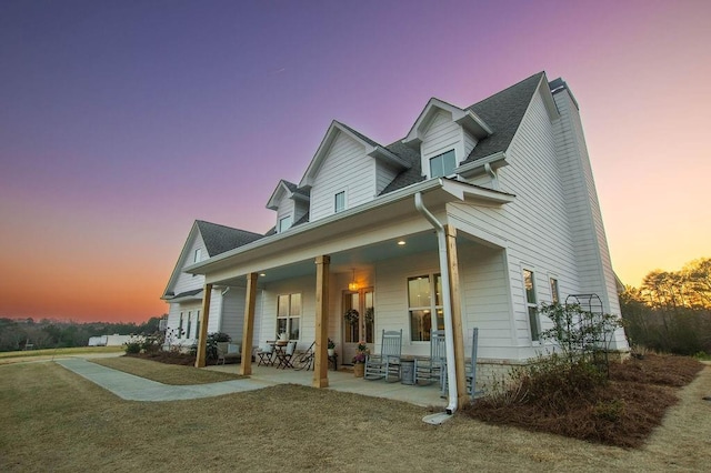 back of property at dusk featuring a lawn