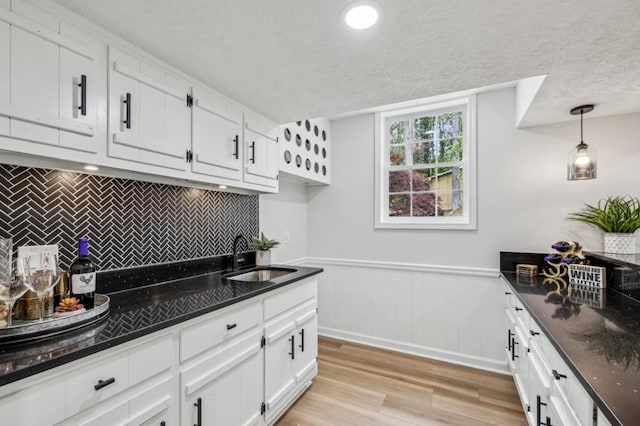 6124 Kings Mountain Ct, Stone Mountain, GA 30087 - kitchen featuring a wainscoted wall, a sink, a textured ceiling, light wood-type flooring, and white cabinets