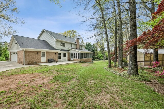 6124 Kings Mountain Ct, Stone Mountain, GA 30087 - rear view of property featuring a sunroom, an attached garage, driveway, brick siding, and a lawn
