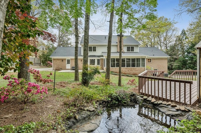 6124 Kings Mountain Ct, Stone Mountain, GA 30087 - rear view of house featuring a sunroom, a wooden deck, brick siding, a yard, and a patio area