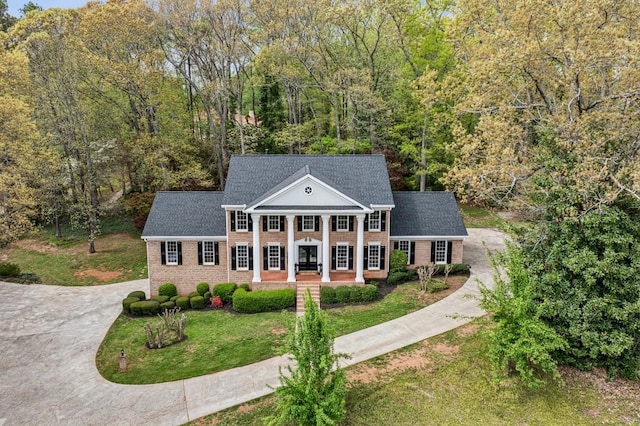 6124 Kings Mountain Ct, Stone Mountain, GA 30087 - greek revival inspired property featuring a forest view, driveway, a front lawn, brick siding, and a porch