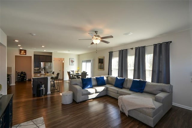 living room featuring ceiling fan, sink, and dark hardwood / wood-style flooring