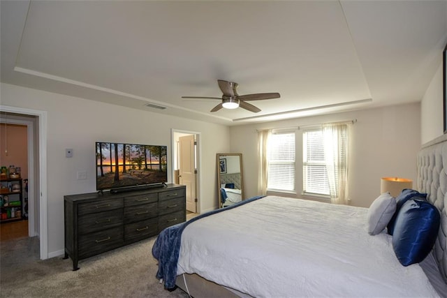 carpeted bedroom with ceiling fan and a raised ceiling