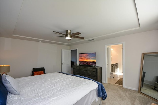 bedroom featuring light carpet, ceiling fan, and a tray ceiling