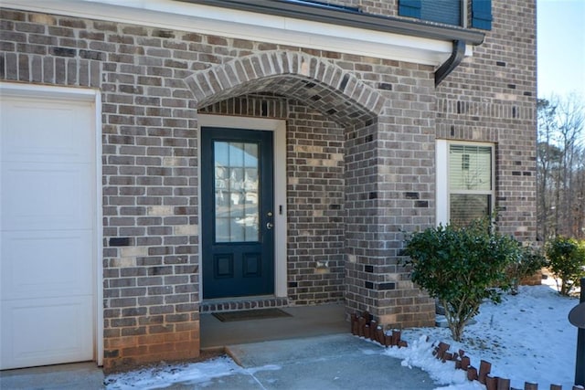 snow covered property entrance with a garage