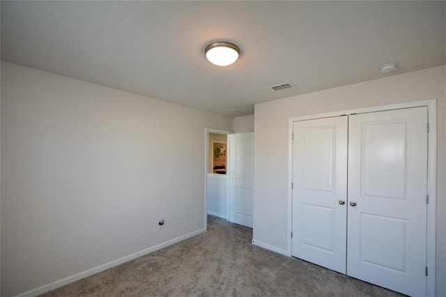 unfurnished bedroom with light colored carpet and a closet