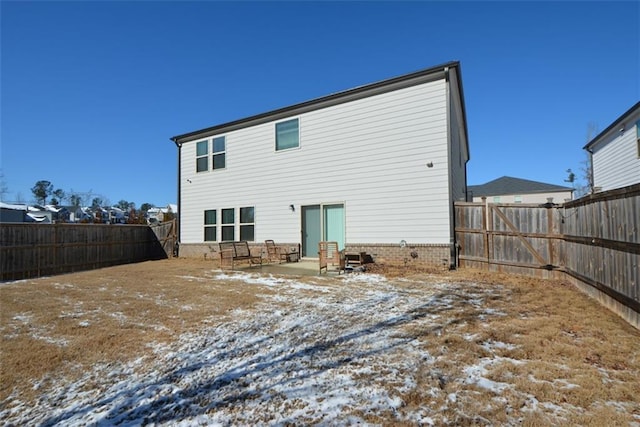 snow covered back of property featuring a patio