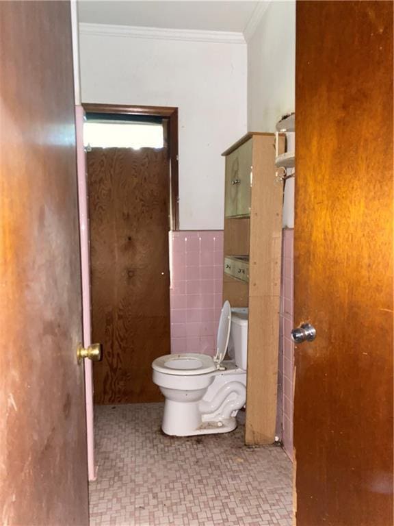 bathroom with toilet, tile walls, and crown molding