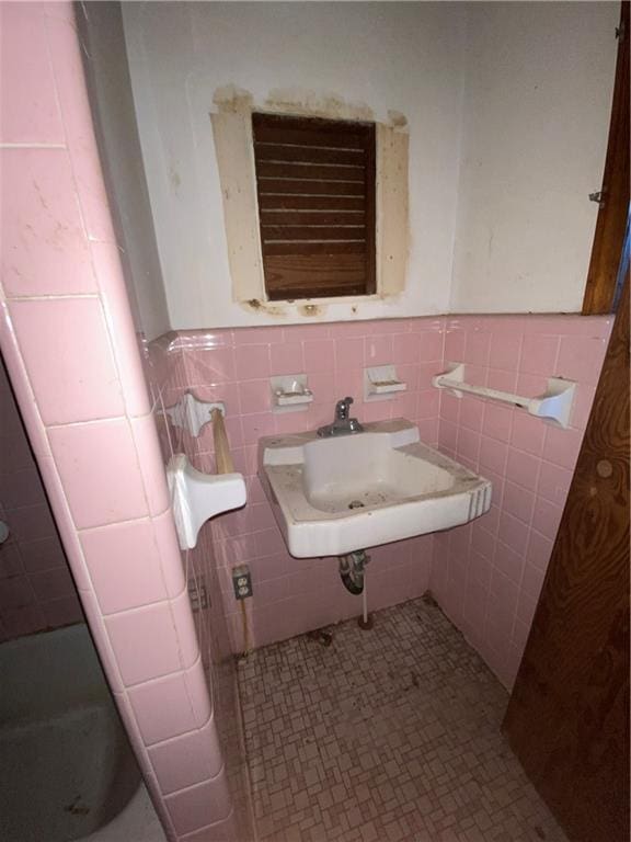 bathroom featuring tile patterned flooring, tile walls, a sink, and wainscoting