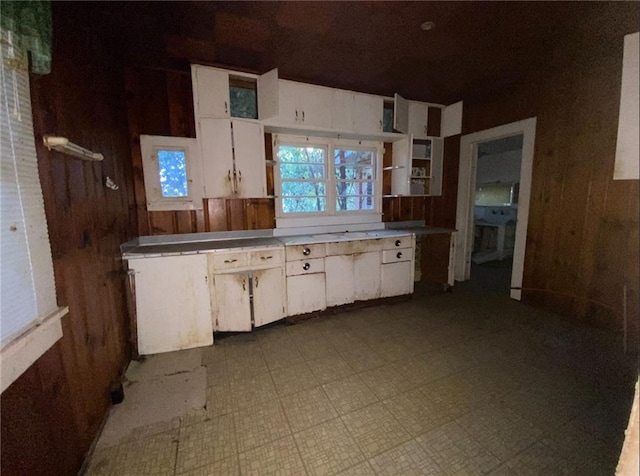 kitchen with dark floors, white cabinets, wood walls, and open shelves