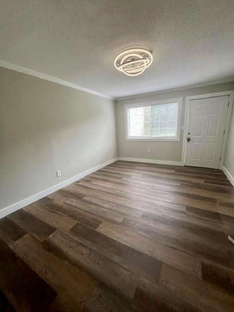 interior space featuring a textured ceiling, crown molding, and dark hardwood / wood-style flooring