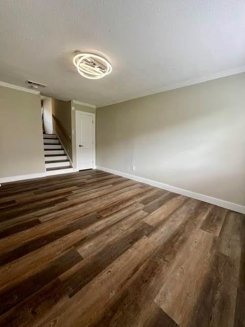 empty room featuring a textured ceiling, crown molding, and dark hardwood / wood-style flooring